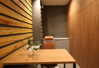 Modern two-person meeting room with warm wood wall panels and a small plant.