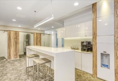 Sleek communal kitchen and breakout area with white cabinetry and breakfast bar seating.