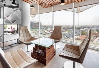 Lounge area with high-back chairs and a wooden pallet coffee table overlooking the city.