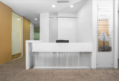 Clean, minimalist white reception desk with warm wooden wall accents.