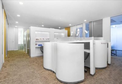 Bright coworking area with unique curved white privacy desks and carpeted flooring.