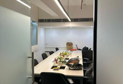 Narrow meeting room featuring a long light-wood table and linear pendant lighting.