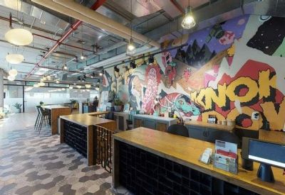 Reception area featuring long wooden desks and a vibrant, colorful street-art mural wall.