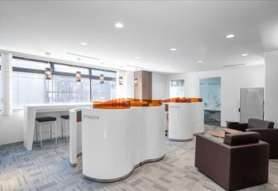 Bright communal coworking area with curved white pods and leather armchairs.