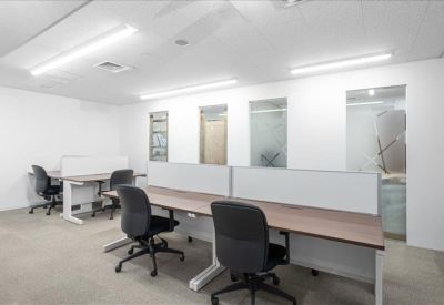 Open-plan office space with rows of modern wooden workstations and task lighting.