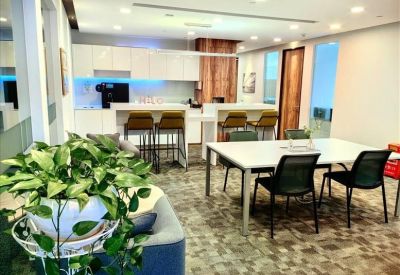 Spacious communal break area with kitchen island, seating, and lush green plants.