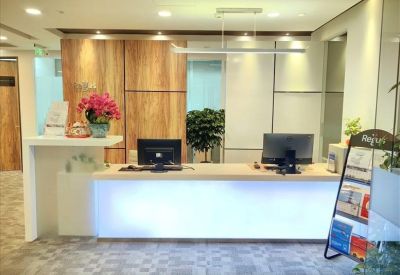Modern reception desk with bright backlighting and wood-paneled feature wall.