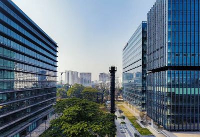 Symmetrical view between two modern glass office towers overlooking a green park.