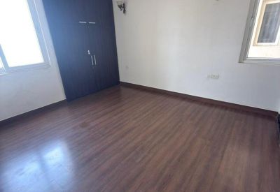 Empty room with polished wooden flooring and a dark wood built-in wardrobe.