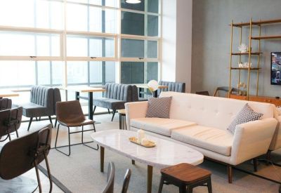 Lounge area featuring a white sofa, marble coffee table, and booth seating by large windows.