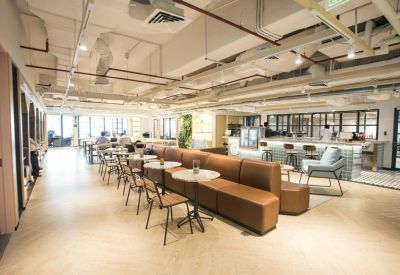 Expansive open-plan coworking space with long leather banquettes and cafe-style seating.