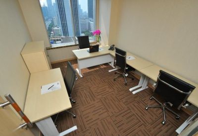 Four-person office suite with light wood desks and brown carpet.