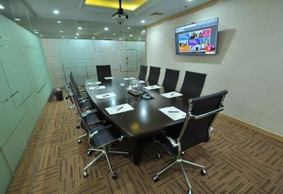 Modern boardroom with a dark wood table, black chairs, and wall-mounted TV.