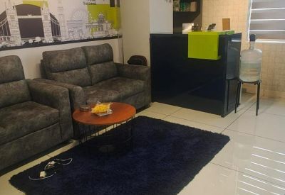 Reception area showing plush grey seating, a coffee table, and a black front desk with lime green accents.