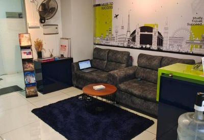 Comfortable reception lounge with grey sofas, a navy shag rug, and a world-themed feature wall mural.