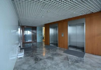 Spacious elevator lobby with wood-paneled walls and grey marble flooring.