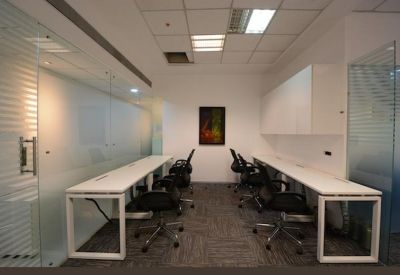 Bright internal office suite with two long white desks and ergonomic chairs.