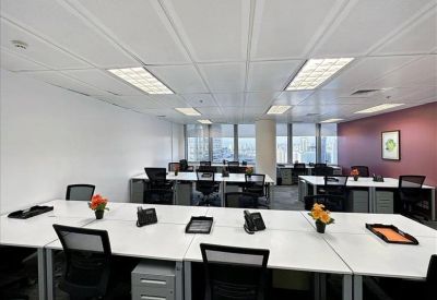 Bright open-plan workspace with white desks and black ergonomic chairs.