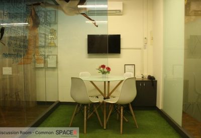 Small common discussion room with white chairs and a green artificial turf floor.