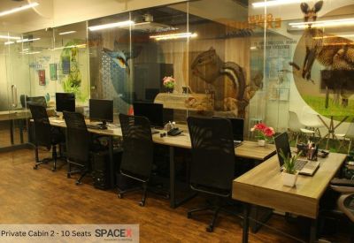 Private office cabin with black mesh chairs and wooden desks behind a glass wall.