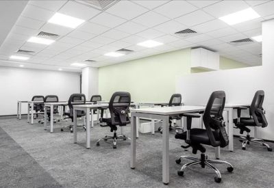 Spacious open-plan workspace with multiple ergonomic black chairs and white desks.