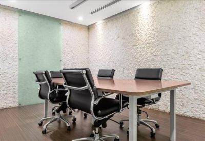 Meeting room with four black leather chairs and textured white stone walls.