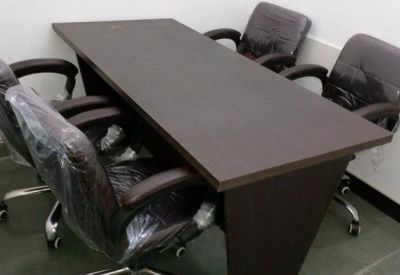 Small meeting room with a dark wood rectangular table and four black chairs.