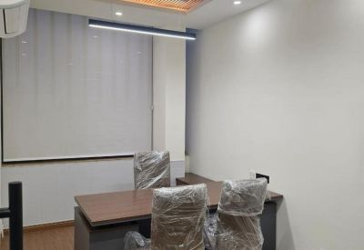 Executive office with a wooden desk and chairs protected by plastic covers.