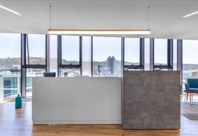 Modern reception area with a minimalist white and grey desk and city views.