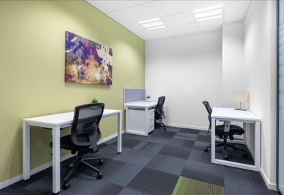 Internal three-person office suite with white desks and a green feature wall.