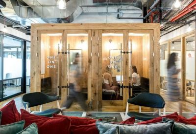 Wooden meeting pods with glass doors in an industrial-style coworking space.
