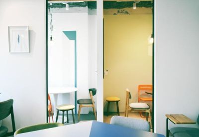 Bright collaborative space with round tables and colourful orange folding chairs.