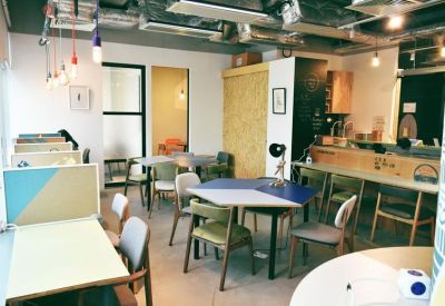 Bright breakout space featuring a hexagonal table, colourful chairs, and industrial ceiling details.