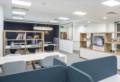 Bright open-plan office featuring wooden shelving units, workstations, and modern blue privacy partitions.