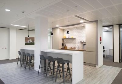 A modern kitchen and dining area featuring white counters and high-top stools at a long island.