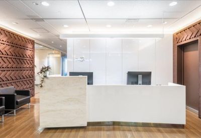 Bright white reception area with a marble front desk and geometric wood-patterned accent walls.