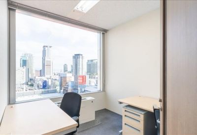 Private office suite for one person featuring a desk, rolling chair, and a large window with city views.