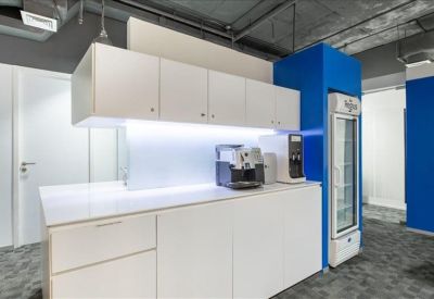 Communal kitchen area with white cabinetry, coffee machine, and a blue wall.