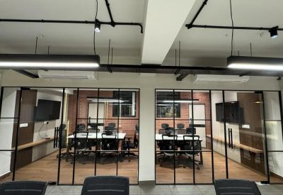 Private glass-partitioned meeting rooms with black frames and modern office chairs.