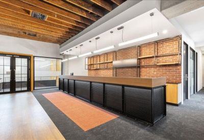 Reception area with a long black desk, brick walls, and industrial-style ceiling beams.