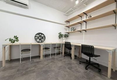 Shared workspace featuring white walls, light wood desks, and shelving.