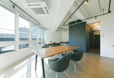 Meeting room with large windows, light wood table, and stylish black chairs.