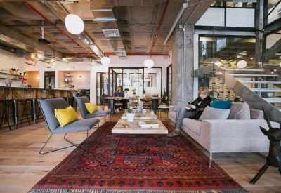Spacious communal area with industrial ceilings, a large rug, and comfortable sofas.