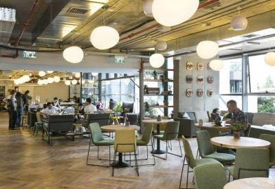 Open-plan dining and workspace area featuring warm wood floors and modern globe pendant lighting.