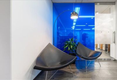 Waiting area with modern black geometric chairs and a vibrant translucent blue glass wall partition.