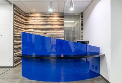 Sleek modern reception area featuring a bold blue curved front desk against a rustic wood-plank feature wall.