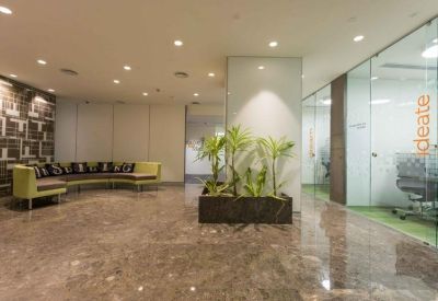 Waiting area with a curved lime green sofa, marble floors, and glass-walled breakout rooms.