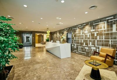 Modern reception lobby with a white geometric front desk, marble floors, and patterned feature wall.