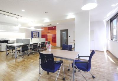 Spacious coworking area with wood-look flooring and a vibrant orange feature wall.