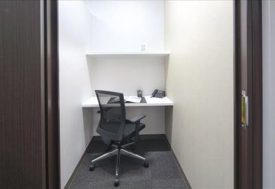 Compact private workstation with an ergonomic chair and a white desk.